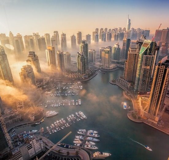 Dubai Marina at night, showcasing illuminated high-rise buildings and luxury yachts. 