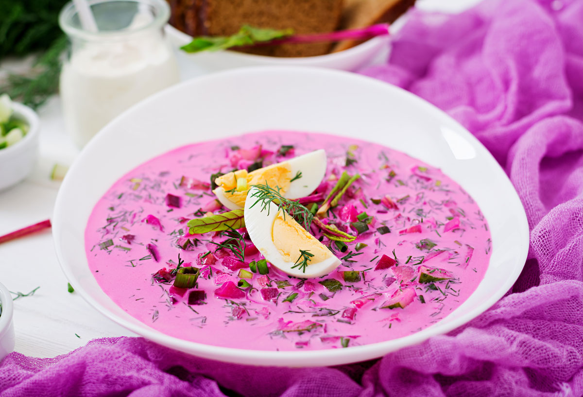 Okroshka served in a glass bowl with dill garnish. 