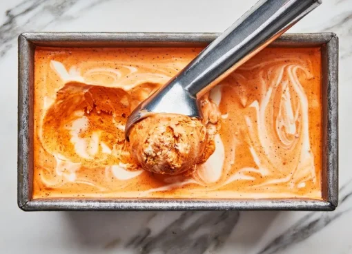Es Krim Thai Tea Lembut: Es krim berwarna jingga cerah dengan tekstur lembut dan rasa khas Thai Tea
