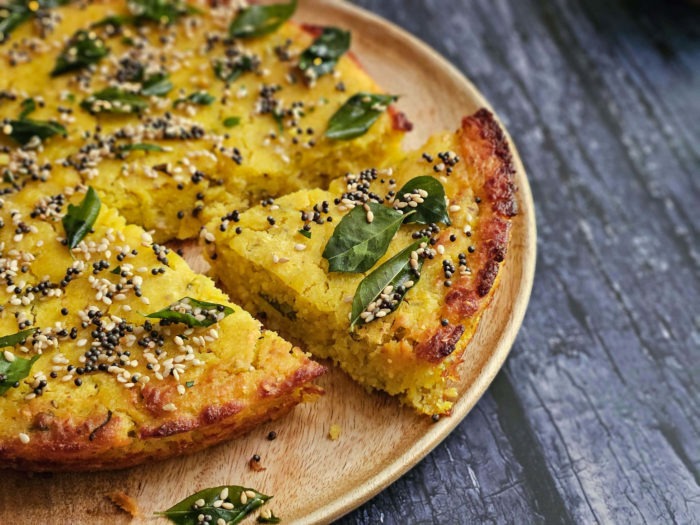 Handvo paired with a cup of masala chai on a rustic wooden table 